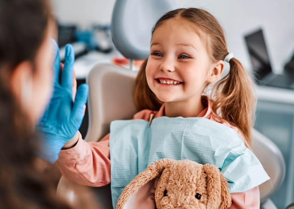 A smiling child high-fiving her dentist in Corona, CA